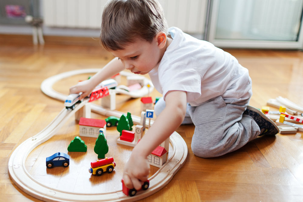 Child playing with a wooden train set.