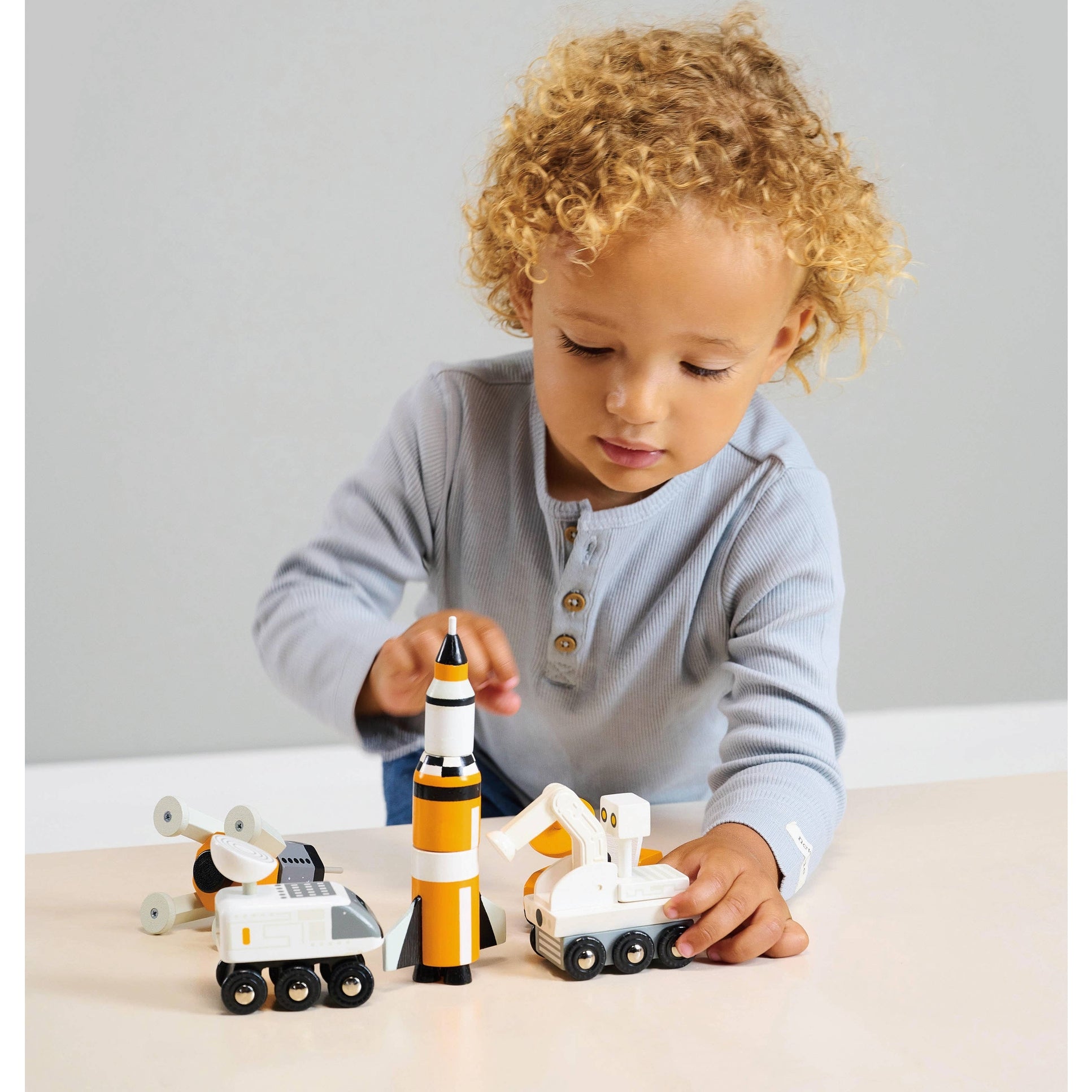 Child interacting with Space Voyager wooden vehicles